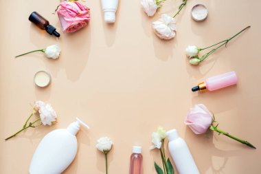 Doğal malzemelerden kozmetik ürünler ve bej bir arka planda çiçek ve gül örnekleri..