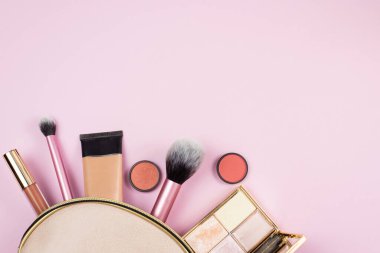 Pembe bir makyaj çantasından pembe bir arka plana dökülen makyaj ürünlerinin genel görünümü. güzellik, moda ve alışveriş konsepti.