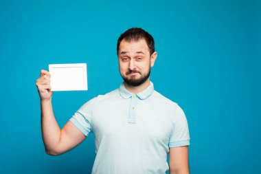 Yakışıklı bir adam elinde beyaz bir çerçeve tutuyor, elinde sahte bir çerçeve ve sevinçle bağırıyor, eğleniyor..