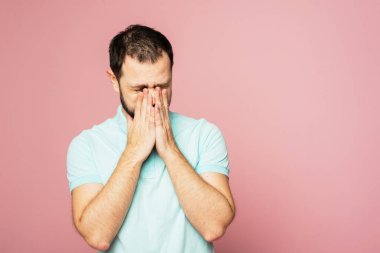 Mavi arka planda mavi tişörtlü bir adam elinde hapşırıyor. Eline hapşıramazsın, dirseğine ya da atkına hapşırmalısın. Kuralların ihlali.