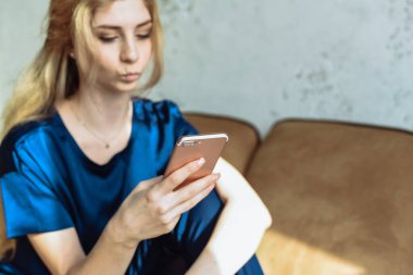 Sosyal ağlar. Genç bir kadın akıllı telefonuyla mesajlaşıyor, bej koltukta rahatça oturuyor, boşluğu kopyalıyor..