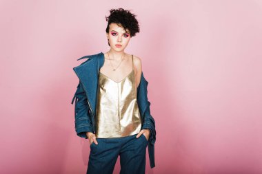 Kot takım elbiseli genç esmer ve pembe arka planda altın rengi bir bluz. Stüdyoda sıradan giyinen bir genç..