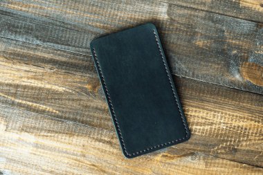 Ahşap bir arka planda deri, lüks telefon kılıfı. Güzel, hakiki deri telefon çantası..