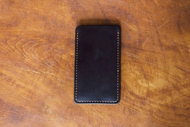 Ahşap bir arka planda deri, lüks telefon kılıfı. Güzel, hakiki deri telefon çantası..