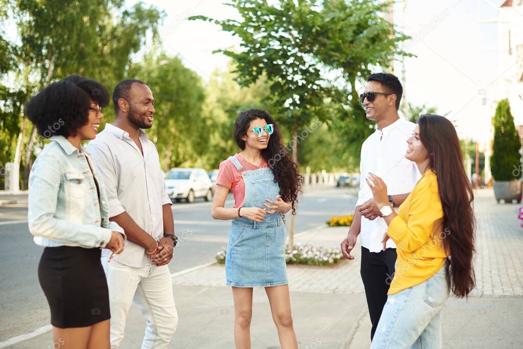 Diverse Group Young People Bonding Outdoors Concept. Communication of friends of different races on the background of the city and the street.