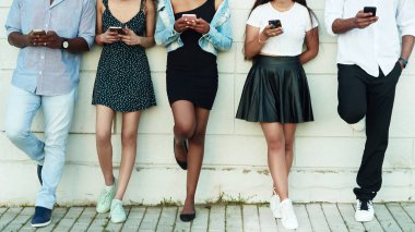 Akıllı cep telefonlarını izleyen bir grup arkadaş. Bir grup çok kültürlü arkadaş açık havada akıllı telefon kullanıyor..