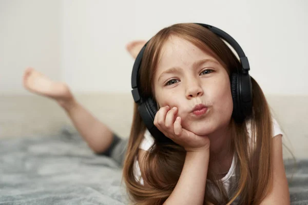 Una Niña Edad Preescolar Escucha Música Cama Burla Mirando Cámara — Foto de Stock
