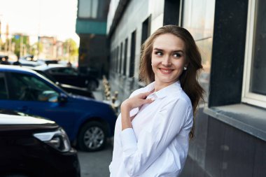 Şehir merkezinde genç bir kız yürüyor. Beyaz gömlekli bir kadının portresi.