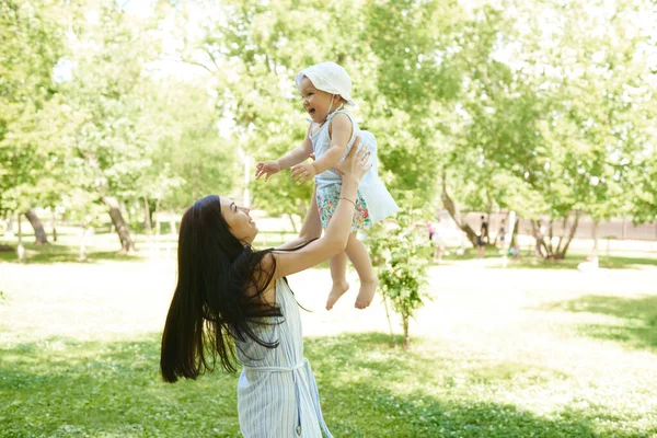 母は娘を投げ出す 母は公園で女の子と遊んでいます — ストック写真