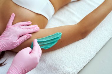 Kozmetik uzmanı epilasyon macunu sürüyor. Ön koldaki kılların alınması prosedürü..