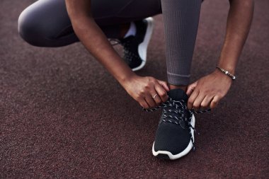 Siyah kız sokakta spor yaparken spor ayakkabılarını bağlar. Açık hava fitness konsepti.