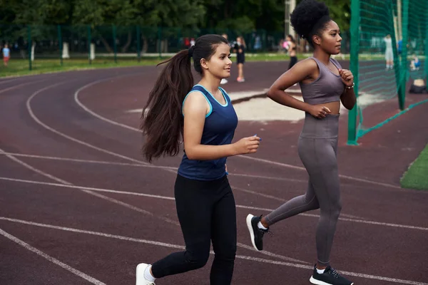 Two young girls go in for sports at the stadium. Jogging in the open air.