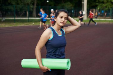Kız alnındaki teri siliyor ve antrenmandan sonra saçını at kuyruğuyla topluyor..