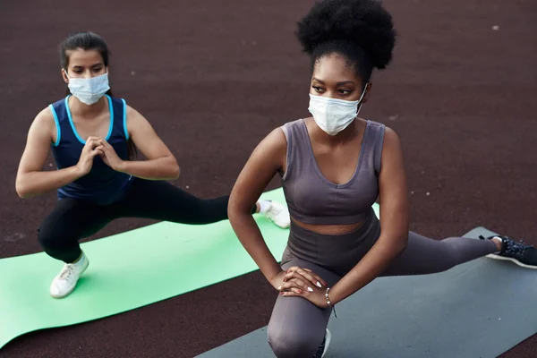 Zwarte en blanke meisjes gaan in de buitenlucht sporten met een beschermend masker. Preventie van coronavirus. Covid-19. Sociale afstand — Stockfoto