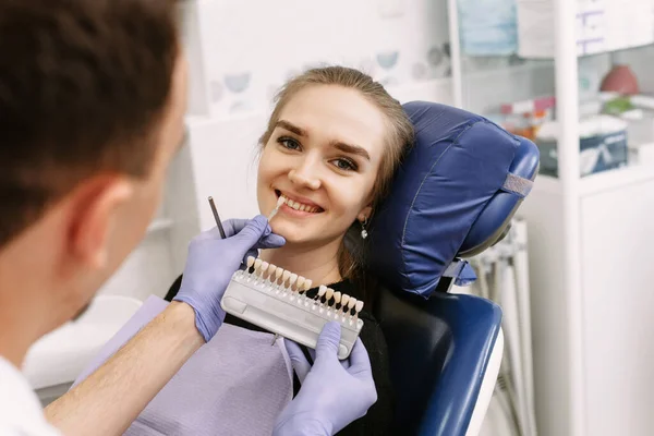 右の日陰を拾うために幸せな女性患者の歯に歯のエナメルスケールからサンプルを適用青い医療用手袋の歯科医 歯の漂白手順 トリミング パノラマ — ストック写真