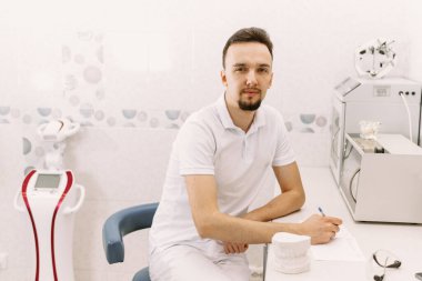 Diş hekimi hastanın tıbbi kayıtlarına bir şey yazıyor. Yapay çenenin yanında. Diş hekimliği randevusu.