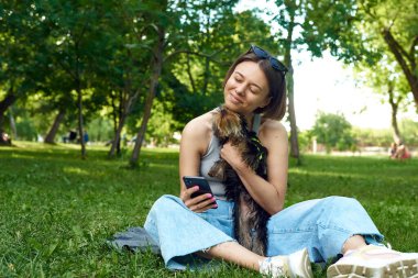 Parkta küçük Yorkshire Terrier 'i olan güzel bir kadın. Yaşam tarzı portresi.