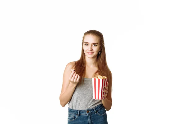 一个穿着休闲装的女孩拿着爆米花盒 凝视着被白色背景隔离的相机的画像 美丽的女人看着相机笑着 Copyspace Template Blog Advertising — 图库照片