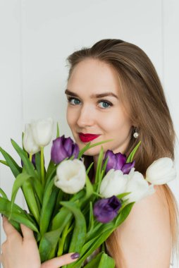 Güzel bir kadın büyük bir buket tutuyor. Bir buket lale taşıyan genç bir kadın..