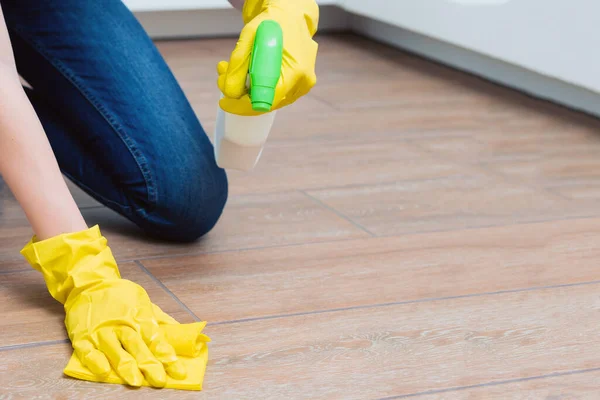 Een meisje wast een vloer met gele handschoenen. Een meisje maakt een kamer schoon met wasmiddelen. — Stockfoto