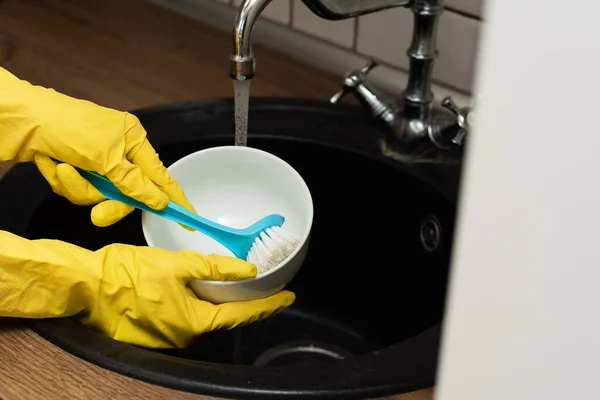 Woman washes dishes in the sink. The concept of spring cleaning and cleaning company.