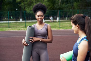 İki genç güzel kız arkadaş dışarıda geçmişteki antrenmanlardan bahsediyorlar. Fitness, yoga ve sağlıklı yaşam tarzı konsepti.