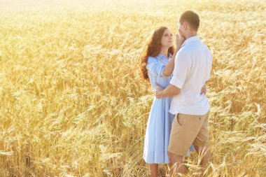 Gülümseyen mutlu çift. Beyaz tişörtlü yakışıklı beyaz adam sarı saçlı, gülümseyen bir kıza nazikçe sarılıyor..