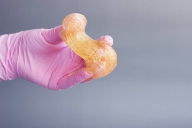 El, şeker ezmesi tutuyor. Arka plandaki epilasyon yapıştırıcısı