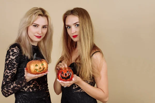Twee Jonge Lachende Vrouwen Houden Halloween Pompoenen Vast Een Beige — Stockfoto