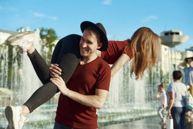 Adam genç bir kadını omuzunda tutuyor. Adam kadını kollarında tutuyor.