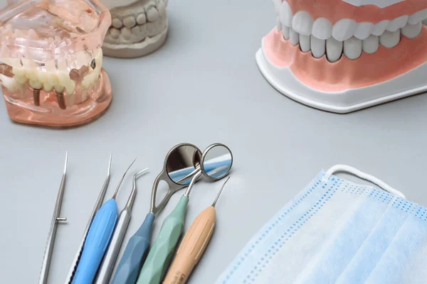 Dentist tools, medical mask and artificial jaws on a blue background.