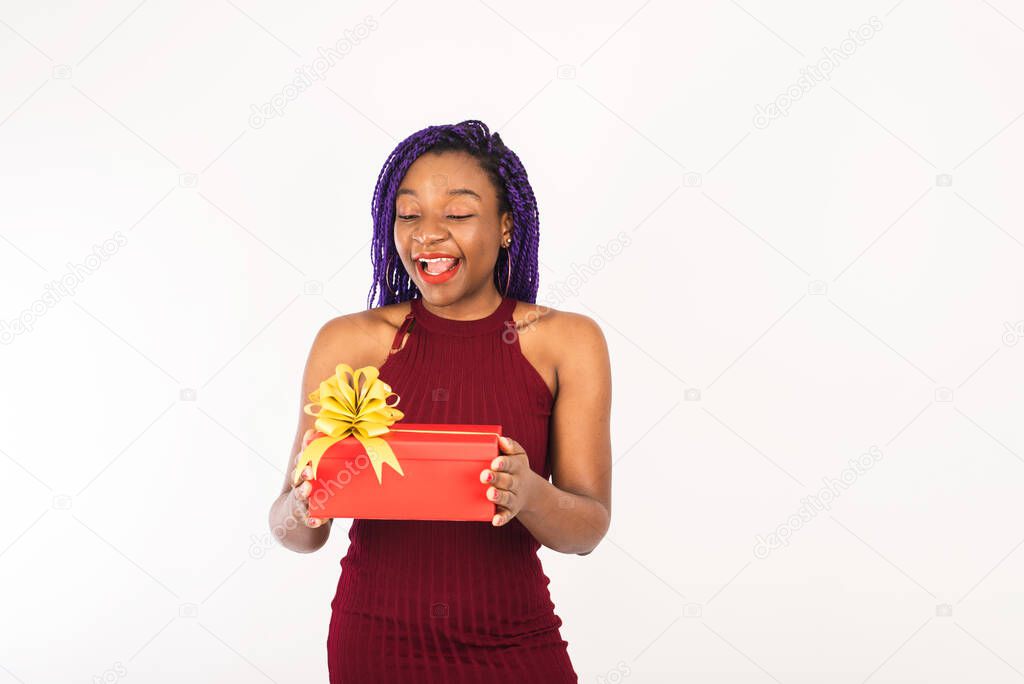 A black young woman enjoys a Christmas red big gift. Young woman smiles and receives gift. Isolated on white background