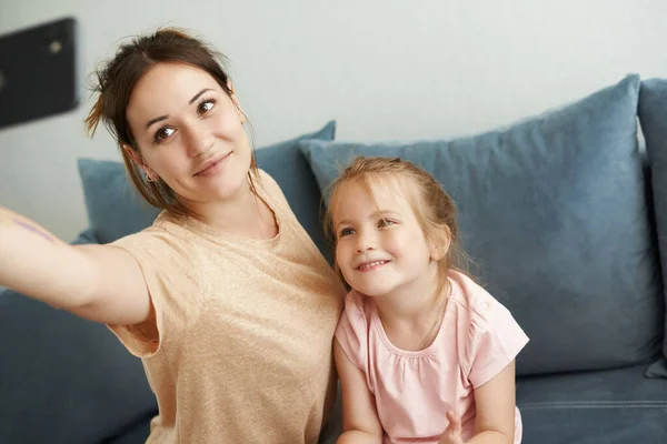 Cute mom and daughter take selfies and smile at the phone camera — Stock Photo, Image