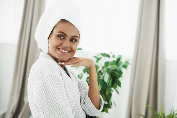 En leende ung kvinna har precis kommit ut ur duschen och står i badrummet. Hudvård, morgonrutin — Stockfoto