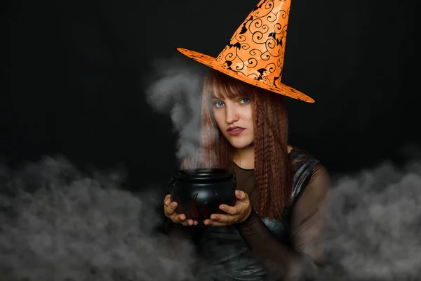 Φωτογραφία μιας νεαρής γυναίκας με κωνικό καπέλο που κρατά ένα τεχνητό δοχείο στο στούντιο — Φωτογραφία Αρχείου