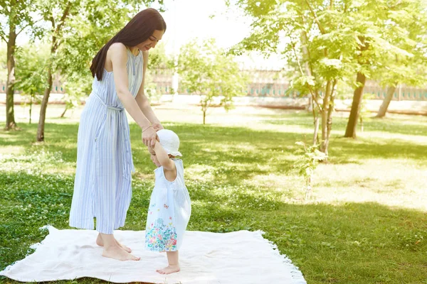 Счастливая мать и маленькая девочка гуляют по парку. Мать и дочь на одеяле в парке. — стоковое фото