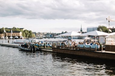 Baltık Denizi'ne bakan bir limanda sıcak bir yaz günü keyfini insanlar. Stockholm, İsveç