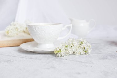 Bir buket beyaz leylak, bir fincan kahve ve eski bir kitap manzarası. Kartpostal. Günaydın..