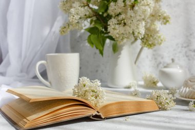 Bir buket beyaz leylak, bir fincan marşmelovlu kahve, bir tabak krema, bir şeker kasesi ve süt sürahisi, eski bir kitap. Kartpostal. Günaydın..