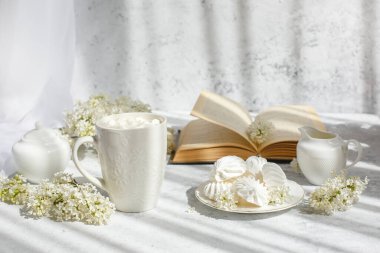 Bir buket beyaz leylak, bir fincan marşmelovlu kahve, bir tabak krema, bir şeker kasesi ve süt sürahisi, eski bir kitap. Kartpostal. Günaydın..