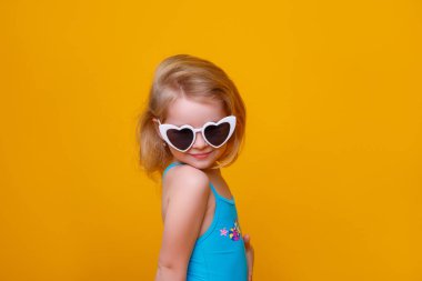 Sarı arka planda mayo ve güneş gözlüklü kız.