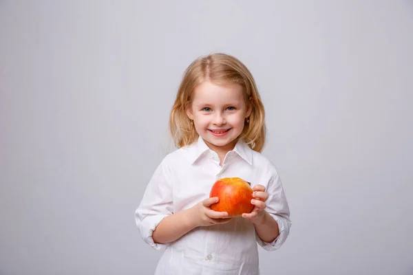 Una Bambina Tiene Mano Una Mela Sorride Uno Sfondo Bianco — Foto Stock