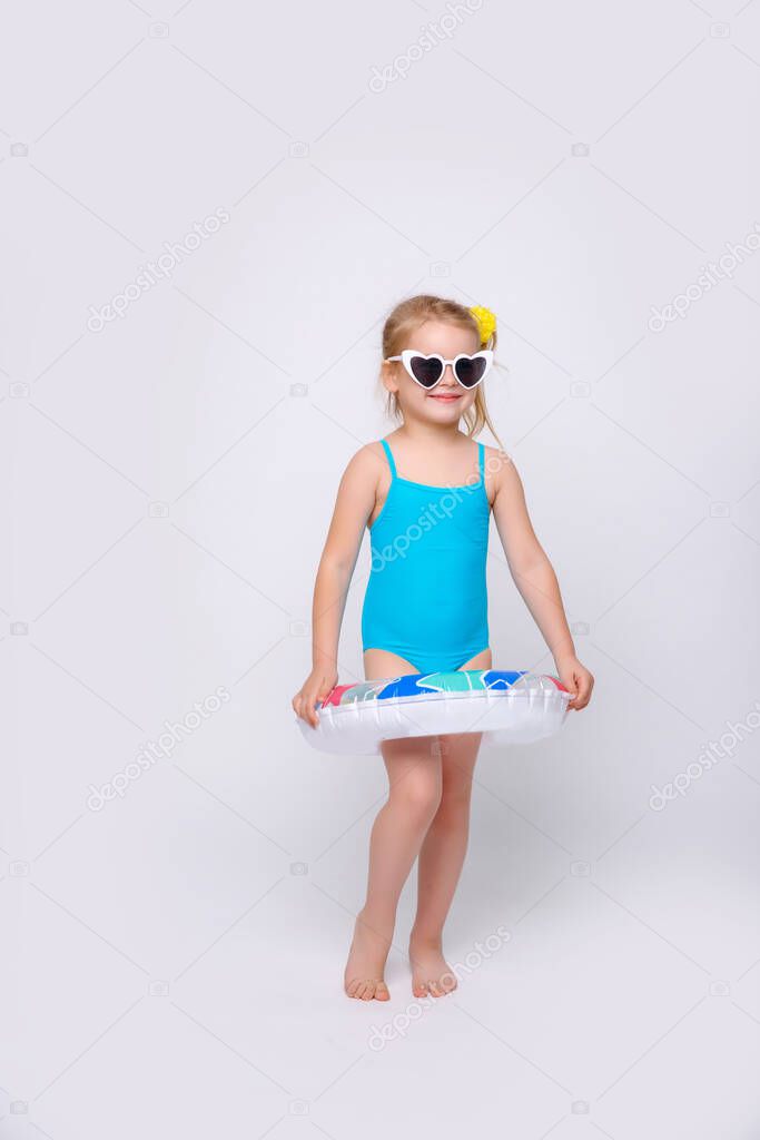 Cute smiling little girl in swimsuit with rubber ring isolated on a white. Fashionable little girl in swimsuit.