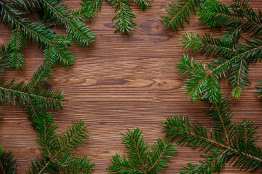 Köknar dalları ve tahta üzerinde çam kozalakları olan bir Noel arkaplanı.