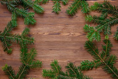 Köknar dalları ve tahta üzerinde çam kozalakları olan bir Noel arkaplanı.