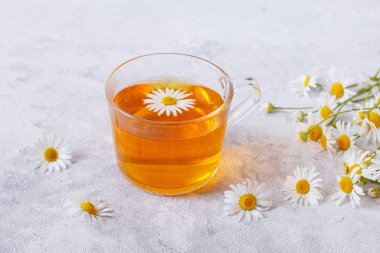 Papatyalı bir fincan çay ve bir buket papatya.