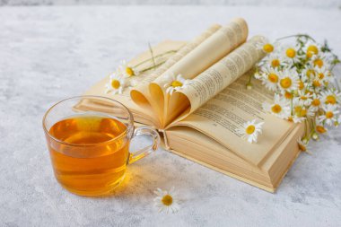 Papatyalı bir fincan çay ve bir buket papatya.