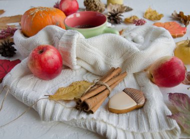 Beyaz bir arka plan üzerinde bir örme beyaz kazak yatıyor, closeup tarçın, elma, yapraklar, meşe palamudu şeklinde gingerbreads