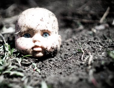 Terk edilmiş köyde bir zemin üzerinde eski kırık korkunç bebek kafası.