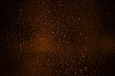 Pencere camındaki yağmur damlaları, ve pencerelerin içinden puslu bir gece manzarası vardı..